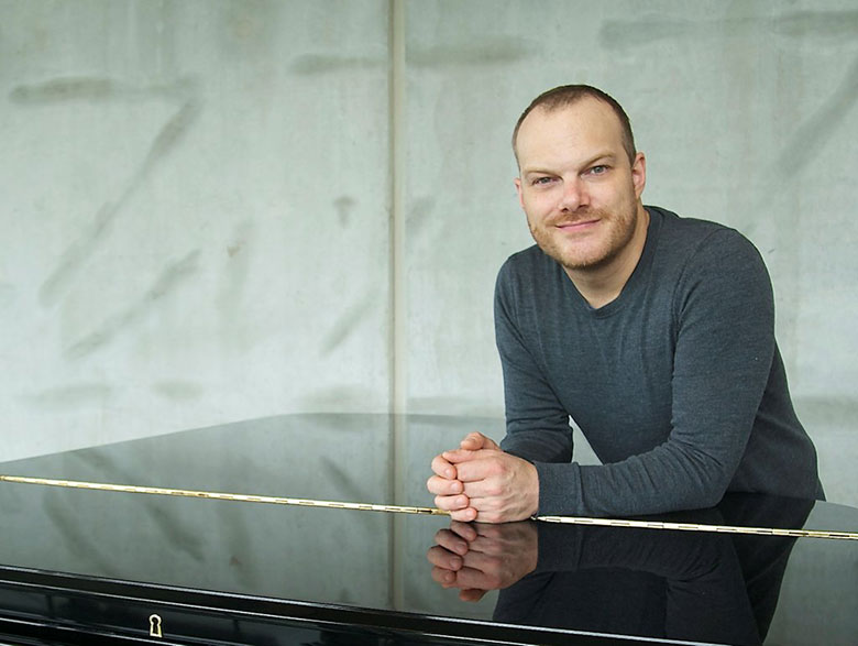 Photo of Lars Vogt leaning on a closed piano lid